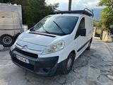 La camionnette blanche est garée à côté d'une remorque sur le parking.
