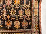 an old rug with a design of flowers and birds on a black ground