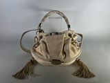 cream colored purse with tassels and handles sitting on a white surface