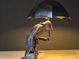a statue of a man holding an umbrella on a table