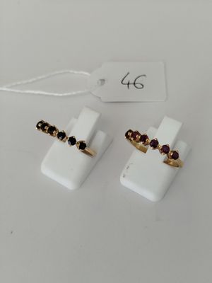 a pair of white and gold rings with garnets on them