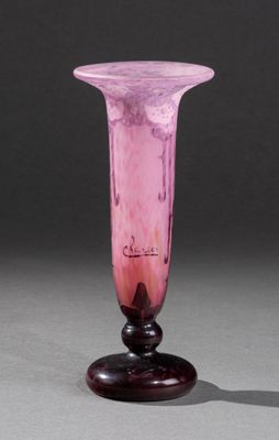 un vase en verre rose posé sur un socle en bois