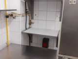 a small kitchen with a stainless steel refrigerator and shelves