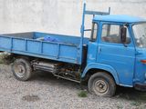 a blue truck parked in front of a white wall