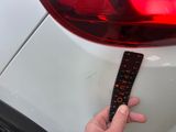 a hand that is holding a ruler on the back of a car