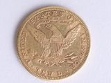 a gold coin with an eagle on it on a white surface