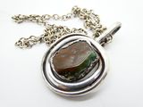 pendentif en métal argenté orné d'une pierre verte et marron, monté sur une chaîne