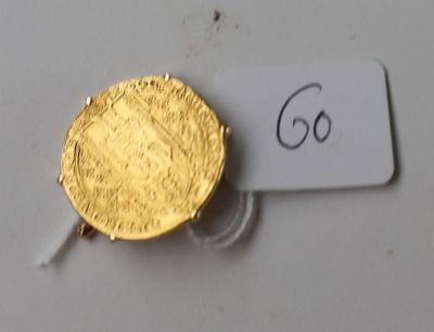 une pièce d'or posée sur une table blanche, avec une étiquette indiquant son prix
