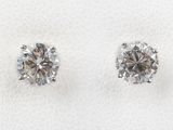 a pair of diamond earrings sitting on top of a white cloth