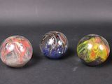 three marble balls with different designs on them on a black surface