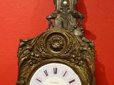 une horloge posée sur une table devant un mur rouge