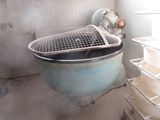 des toilettes sales dans une salle de bains sale, avec un panier en métal posé dessus