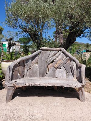a wooden bench made out of logs on the side of the road