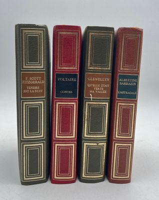 four books are lined up in a row on a white surface