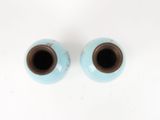 two small blue vases sitting on a white surface