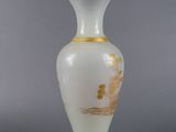 a white vase with gold decoration on it on a gray surface