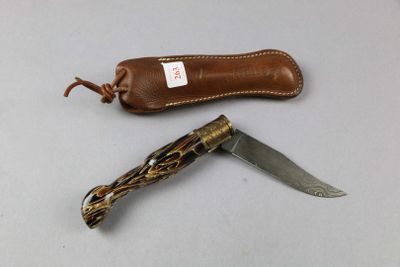 a knife that is laying on a table next to a leather case