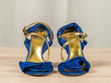 blue and gold high heeled sandals on a wooden table