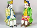 paire de figurines en céramique représentant des clowns assis sur une souche d'arbre