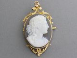 a close up of a gold and white cameo of a woman
