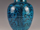 un vase bleu orné de motifs noirs sur un fond blanc