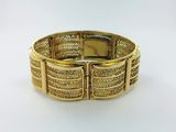 gros plan d'un bracelet en or sur une surface blanche