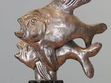 statue of a fish on a marble base with a gray background