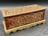 une boîte rouge et dorée posée sur une surface grise