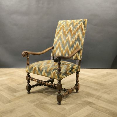 une chaise en bois avec une assise rembourrée à motifs, posée sur un parquet