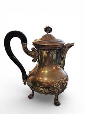 a silver coffee pot with a black handle on a stand