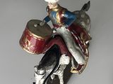 a figurine of a man riding a horse with a drum
