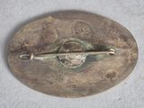 a silver brooch with a pin on it on a white surface