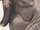 a statue of a laughing buddha holding a stick