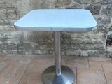 a small table with a blue top sitting on a brick floor