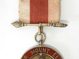gros plan d'une médaille sur une surface blanche avec un ruban rouge