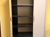 une armoire haute avec des étagères, placée dans un coin de la pièce