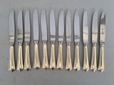 six silverplated knives and six knives on a table
