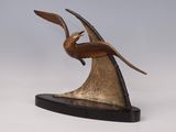 sculpture en bronze représentant un oiseau posé sur un socle, sur fond blanc