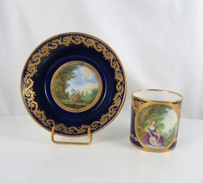a close up of a cup and saucer with a painting on it