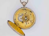 a yellow pocket watch with a silver case on a white surface
