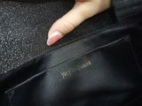 a woman ' s hand holding onto a black purse