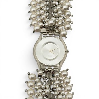 une image représentant une montre-bracelet ornée d'un collier de perles