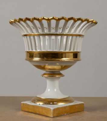 une photo d'un vase blanc et doré posé sur une table en bois
