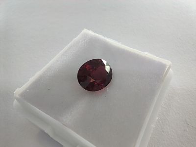 a close up of a red garnet stone on a white surface