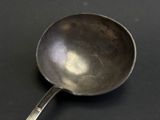 a silver spoon with a handle on a black surface