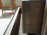 a wooden table with a drawer on it and a chair in the background