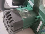 a close up of a green and black corded saw