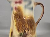 a small pitcher with a rooster on it on a table