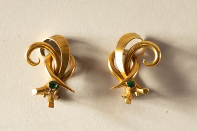 paire de boucles d'oreilles dorées ornées de pierres vertes sur un fond blanc