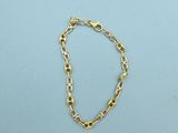 a close up of a gold chain bracelet on a blue surface